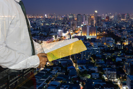 Businessman holding a book standing against night city building background in double exposureの写真素材
