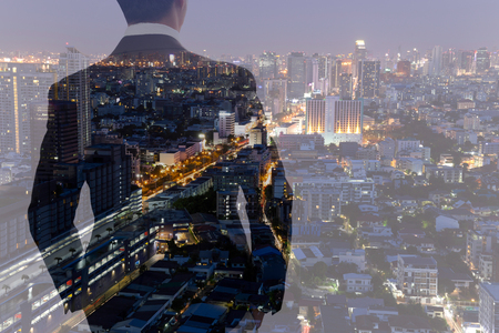 Businessman looking at city building at night in double exposureの写真素材