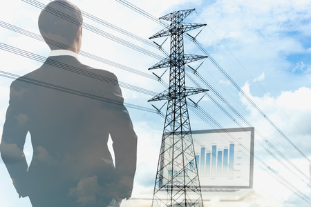 Double exposure of businessman with high voltage electric pole and laptop in backgroundの写真素材