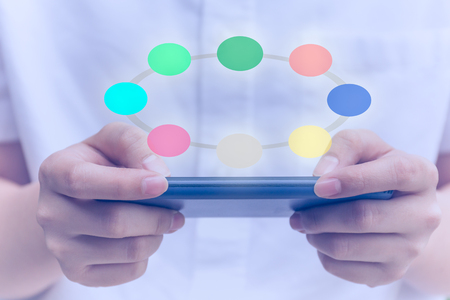 Conceptual young people using cell phone with colorful circle digital iconの写真素材