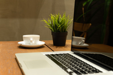 Business still life selected coffee cup with laptop on wooden table in cafeの写真素材