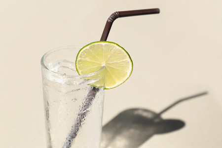 Glass of fresh drinking water with straw and slice of limeの写真素材