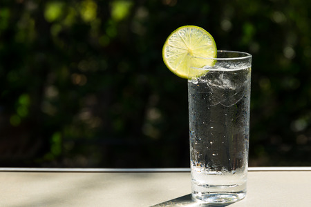 Glass of fresh drinking water with slice of lime on the tableの写真素材