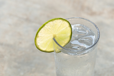 Glass of fresh drinking water with slice of lime in blur backgroundの写真素材