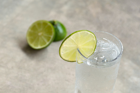 Glass of fresh drinking water with slice of lime in blur background