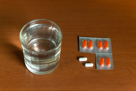 Conceptual glass of water and pills on wooden tableの写真素材