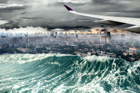 Conceptual Air plane with nature disaster city destroyed by Tsunami wavesの写真素材