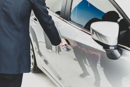 Family looking for new car with salemans hand on handle opening a car door in matteの写真素材