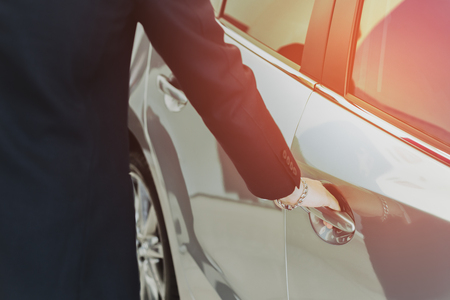 Salemans hand on handle opening a car door with sunlight in matteの写真素材