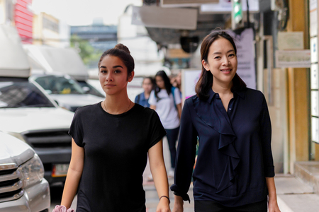Mother and daughter walking in on street doing shoppingの写真素材
