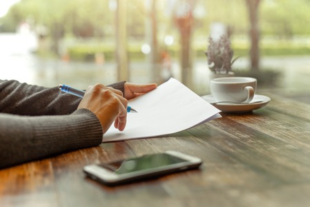 Busineswoman hand holding pen over  paperwork on wooden tableの写真素材