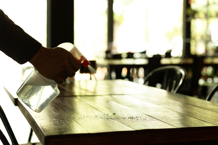 Silhouette waiter cleaning the table with disinfectant spray in a restaurant.の写真素材