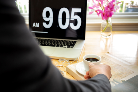 Business man holding cup of coffee with laptop computer on wooden tablet.の写真素材