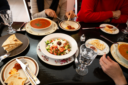 Family dinner with Greek salad and on the dinner table with glass water.の写真素材