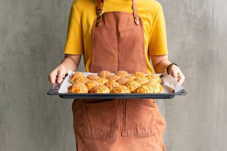 Young woman holding tray with fresh Choux cream or eclair.の写真素材