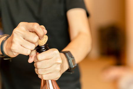 Hand opening bottle of champagne for celebration indoor.の写真素材