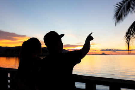 Silhouette couple man hand pointing out in sky at sunset over the sea in koh samui islandの写真素材