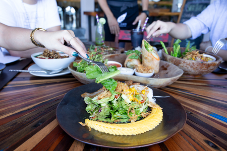 Woman hand with fork eating vegetables salad with friends Healthy clean eating cocept.の写真素材