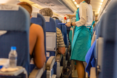 Flight attendant serve drink to passengers on board.