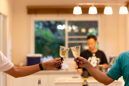 Friends party celebration with clinking glasses of white wine at home.の写真素材