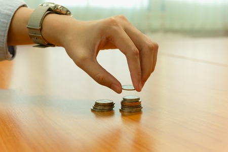Hand putting coin on coins stack with Savings, Finance concept.の写真素材