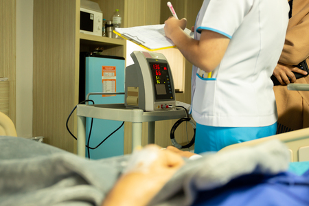 Nurse checking blood pressure on monitor screen for patient health in hospital.の写真素材