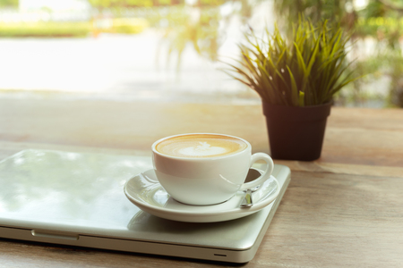 Coffee cup with laptop computer on wooden table and morning light.の写真素材