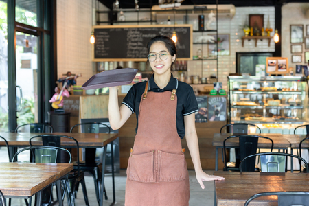 Portrait of waiteress holding empty tray in a coffee shop.の写真素材