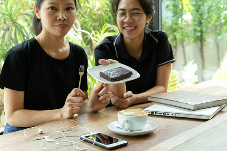 Female friends having coffee break with brownie cake in coffee shop.の写真素材
