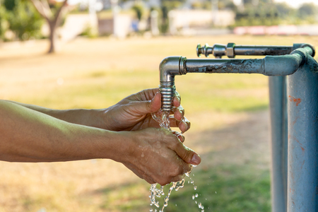 Man washing hands from plumbing tap outdoor.の写真素材