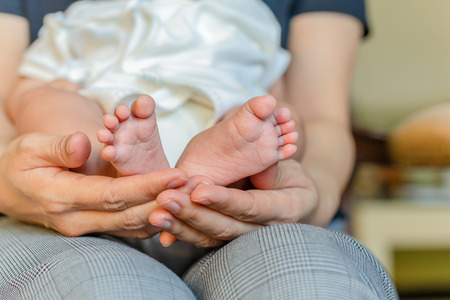 Newborn baby feet in her mum is hand.の写真素材