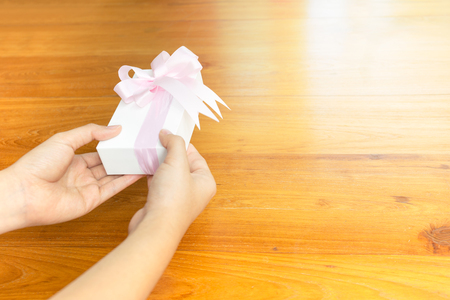 Woman hand give wrapped valentine present with pink ribbon.の写真素材