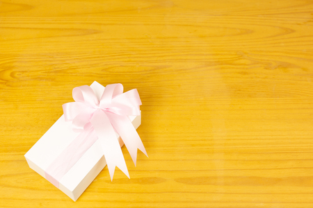 Gift box with pink ribbon on woodenの写真素材