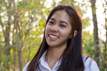 Portrait of asian college woman smiling in blur background witn sunlight.の写真素材