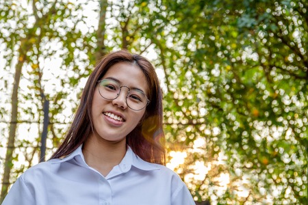 Portrait of asian college woman smiling in blur background witn sunset.の写真素材