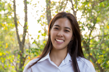 Portrait of asian college woman smiling in blur background witn sunlight.の写真素材