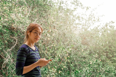 Portrait teenager woman with eyes glasses listen to music with earphone.の写真素材