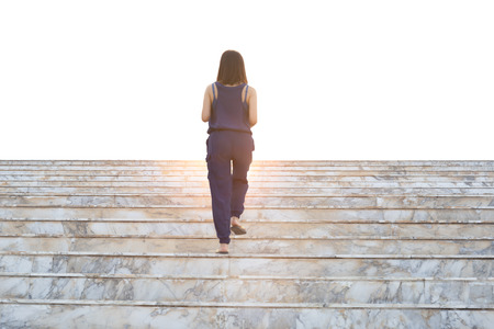 Rear view of woman walking up the stairs isolated in white background.の写真素材