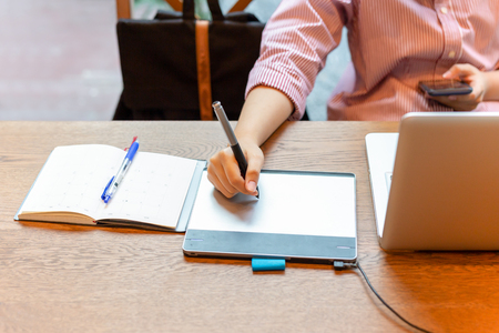 Graphic designer using digital tablet with laptop on the desk.の写真素材