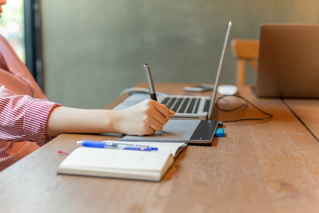Graphic designer using digital tablet with laptop on the desk.の写真素材