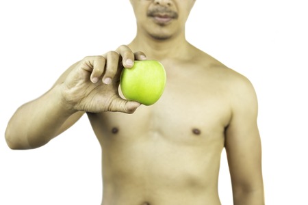 Healthy naked man holding a fresh green apple isolated in clipping path.の写真素材
