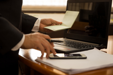 Business financial hand hold book statement and work with laptop.の写真素材