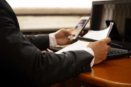 Businessman working on documents paper using cell phone and laptop.の写真素材
