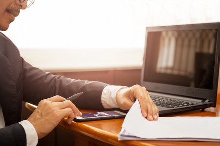 Businessman working on documents paper using cell phone and laptop.の写真素材