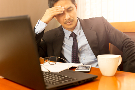 Businessman leaning with hand on his head on eyes closed feeling sleepy.の写真素材