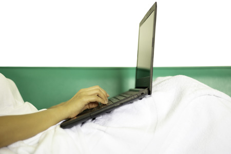 Woman hand typing on keyboard laptop lying in green couch.の写真素材