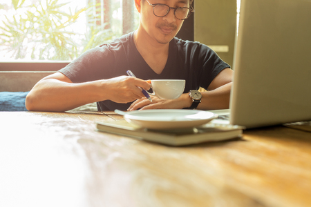 Portrait asian man with glasses having coffee break working with laptop.の写真素材