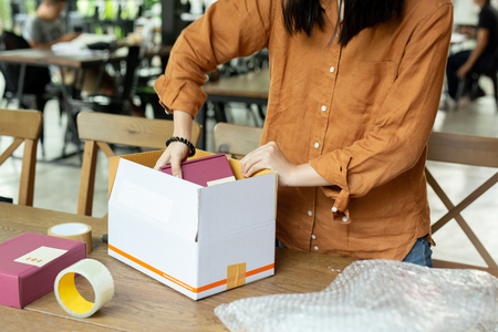 Startup small business woman owner packing cardboard box at workplace.の写真素材