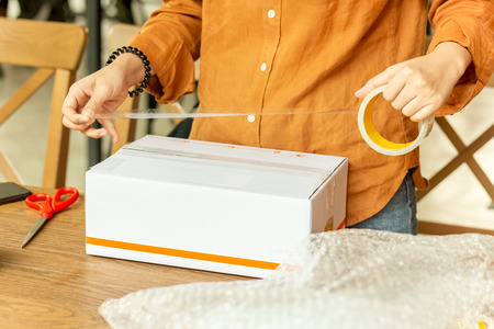 Startup small business woman owner packing cardboard box at workplace.の写真素材