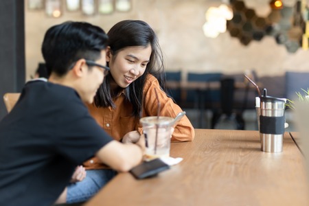 Happy female friend looking at cell phone in cafe.の写真素材